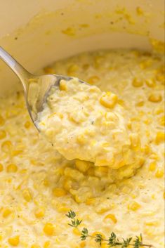 a ladle full of corn is being held over the soup in a white pot