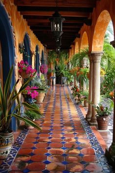 an outdoor walkway with potted plants and hanging lanterns on either side, surrounded by blue and orange tiles