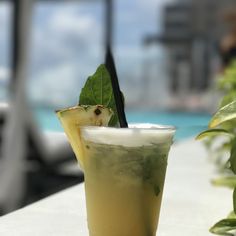 a drink sitting on top of a white table next to a green leafy plant