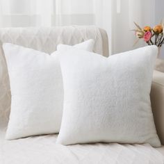 two white pillows sitting on top of a couch