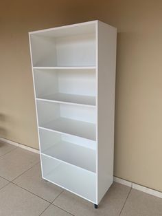 a white book shelf sitting on top of a tiled floor