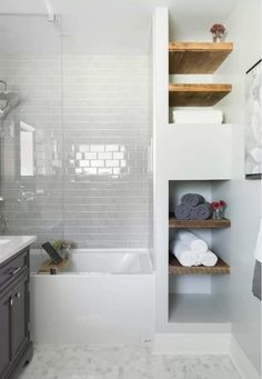 a bathroom with gray cabinets and white tiles on the walls, along with a bathtub