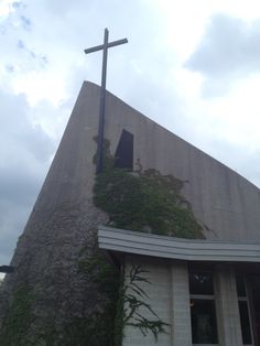 a cross on the side of a building with ivy growing up it's side