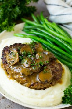 mashed potatoes with mushrooms and gravy served on a plate next to green beans