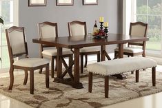 a dining room table with chairs and a bench in front of a window on an area rug