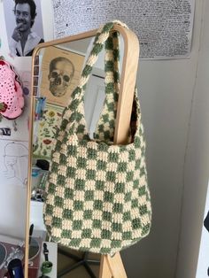 a green and white bag sitting on top of a wooden stand next to a mirror