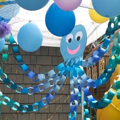 some blue and yellow balloons are hanging from the ceiling in front of a building with a brick wall