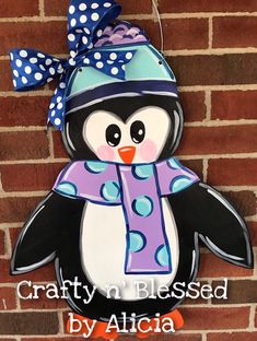 a penguin with a hat and scarf on it's head is hanging from the side of a brick wall