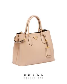 Find PRADA Saffiano Leather Double Bag on Editorialist. The Prada Saffiano Leather Double Bag is crafted from Saffiano leather and features leather handles, a detachable and adjustable leather shoulder strap, a leather name tag with metal details, metal hardware, and a metal lettering logo on a leather triangle at the front. The bag features snap closure on the sides and a nappa leather lining with flap pocket. It also has small feet on the bottom. High-end Epsom Leather Bag For Everyday Luxury, Chic Saffiano Leather Shoulder Bag With Palladium Hardware, Chic Epsom Leather Shoulder Bag With Palladium Hardware, Chic Shoulder Bag In Epsom Leather With Palladium Hardware, Evening Saffiano Leather Shoulder Bag With Palladium Hardware, Luxury Leather Handle Satchel For Everyday Use, Luxury Epsom Leather Shoulder Bag For Evening, Luxury Epsom Leather Satchel With Top Handle, Modern Saffiano Leather Shoulder Bag With Handles