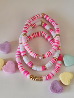 several bracelets with hearts and beads on a white table next to other heart shaped objects