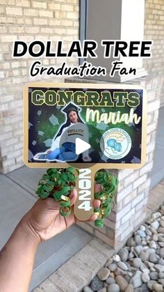 the dollar tree graduation fan is holding it up in front of a brick building with text overlay that reads dollar tree graduation fan