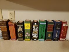 a row of books sitting on top of a counter next to a wall mounted light switch