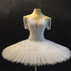 a white tutu dress with flowers on the skirt and beaded trimmings