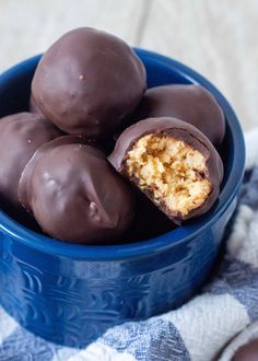 a blue bowl filled with chocolate covered donuts on top of a tablecloth next to an orange and white towel