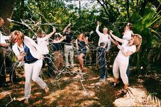 a group of people standing around each other in front of trees and barbed wire on the ground