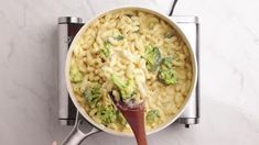 someone is stirring some pasta with broccoli in a pot