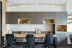 an office space with desks and chairs in the center, open shelving on the wall