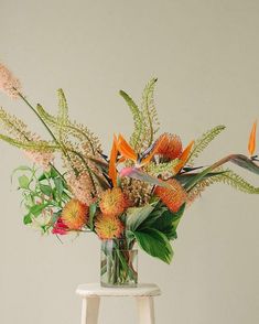 an arrangement of flowers in a vase on a stool