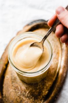 a spoon in a jar filled with mayonnaise on top of a wooden tray