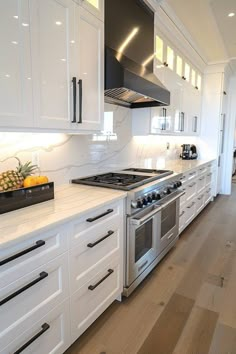 a kitchen with white cabinets, stainless steel appliances and an island in front of the stove