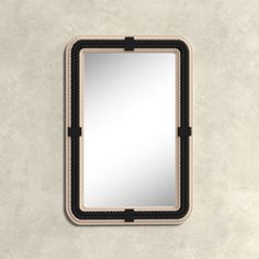 a black and white mirror hanging on the side of a wall with an iron frame