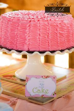 a pink cake sitting on top of a table next to a card and other items