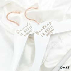 two white hangers with gold writing on them