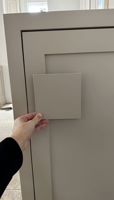 a person is opening the door to a kitchen cabinet that has been painted gray with white trim