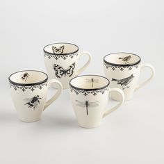 four coffee cups with designs on them sitting next to each other in front of a white background