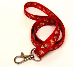 "Colourful daisy print on red background neck strap lanyard 15mm (non-detachable clasp, 15mm width) Bright white and yeloow flowers on a red background. High quality UK printed ID holder lanyards, printed on both sides, fitted with a metal clip, to be worn around the neck to carry ID, access cards, keys etc.   Product code : H-270 Hand made in the UK Size: 93cms  (36\") Width : 15mm  (0.78\") Silver metal clip *  Great quality and value *  Beautifully coloured, bright vivid sublimation print *  Lightweight *  Smooth polyester fabric remains comfortable to wear *  Long lasting metal trigger clip UK manufacturer and seller All prices include free UK post & packing All lanyards are individually packed Available in 3 options: Standard lanyard with just a metal hook Safety breakaway lanyard wit Personalized Lanyards, Custom Lanyards, Background High Quality, Key Lanyard, Uk Post, Document Holder, Printing Business, Daisy Print, Id Holder