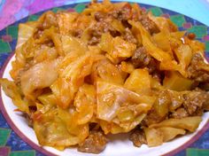 a white plate topped with pasta and meat covered in sauce on top of a colorful table cloth