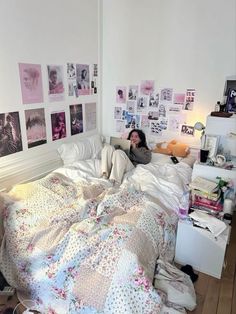 a woman laying in bed with lots of pictures on the wall