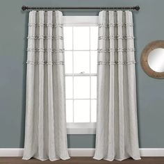 the curtains are hanging in front of a window with a mirror on top of it