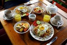 a wooden table topped with plates of food and glasses of orange juice on top of it