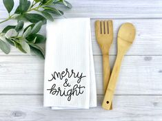 two wooden utensils sitting on top of a white towel next to a plant