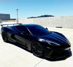 a black sports car parked in front of a cement wall and concrete flooring area