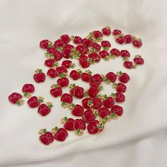 a bunch of red strawberries with green leaves on white fabric, surrounded by gold - plated beads