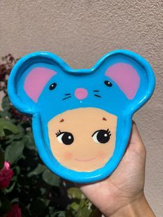 a hand holding up a blue bear shaped plate