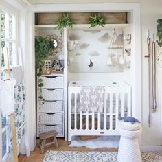 a baby's room with white furniture and plants on the wall, along with a crib