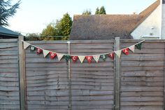 a wooden fence with a christmas banner hanging from it's side in front of a house