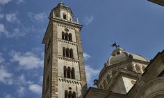 a tall clock tower towering over a city under a blue sky with wispy clouds