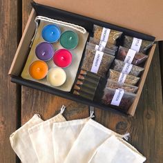 an open box filled with candles next to some tea bags and napkins on a wooden table