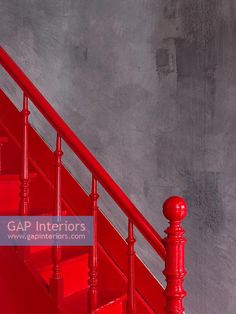 a red stair case next to a gray wall