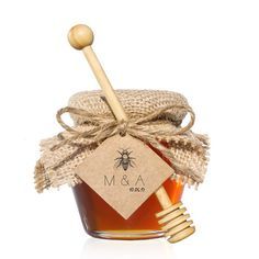 a jar of honey with a wooden stick and label on the lid that says m & a