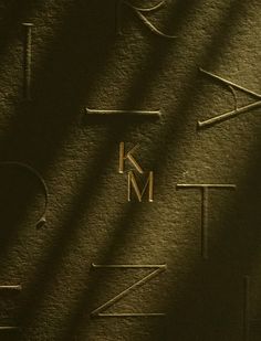 the letters k and m are made up of metal bars on a black surface with shadows