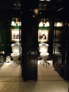 two white toilets sitting in a bathroom next to each other on top of a tiled floor