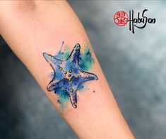 a blue starfish tattoo on the left forearm and right arm with watercolor splashes