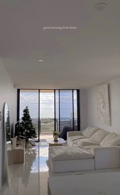 a living room filled with white furniture and large windows