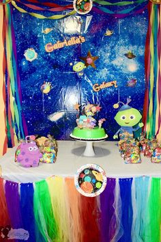 a table topped with lots of cakes and desserts next to a colorful wall covered in stars