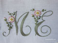 an embroidered design with flowers and the letter e on it's side, next to a pair of scissors